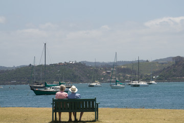 Fototapeta na wymiar A older couple sit on border coast seeng the sea