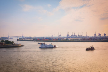 Exploration tour through the port of Hamburg on the background of cranes and a ferry