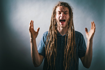 Young man screaming on a solid background