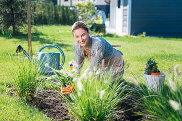Joyful weekend. Beaming appealing woman wearing beige apron enjoying her weekend greatly while...