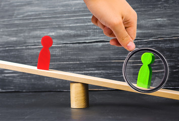 wooden figures of people. rivals in business stand on the scales. trial. conflict. victory and...