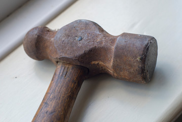 An old hammer head tool with a wooden handle