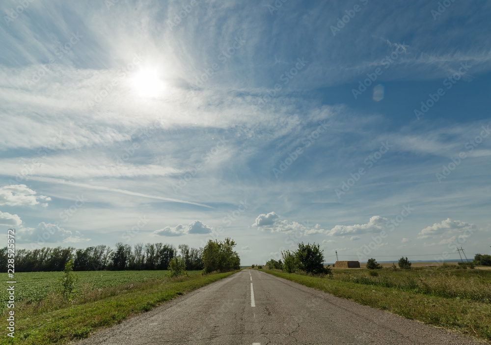 Wall mural Bright clouds in the blue sky above the road.