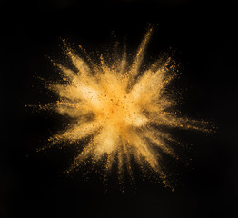Golden powder explosion on black background.
