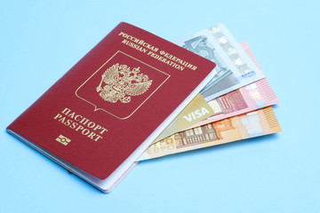 Euro banknotes and VISA card enclosed in a foreign Russian passport isolated on a blue background. Travel to Europe.
