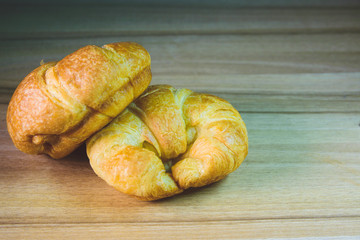 Tasty buttery croissants on old wooden table.