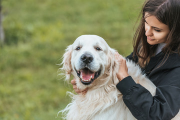 beautiful young woman stroking adorable retriever dog in park