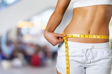 Slim young woman measuring her thin waist