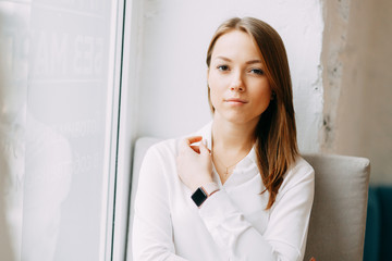 Young blogger girl with coffee sitting and working in a cafe. Bright portraits in the coffee shop, smiles and happy eyes. Business woman, strict style