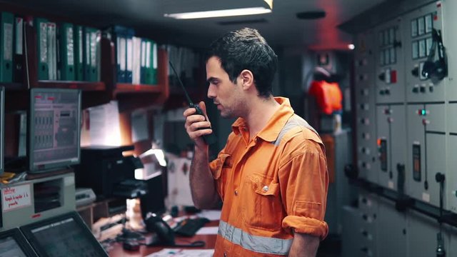 Marine Engineer working on radio communication at Engine Control room ECR. Vessel communication with VHF and UHF walkie-talkie radio