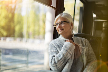 Senior Woman Looking Through Window While Traveling In Bus
