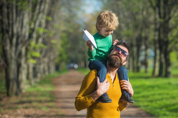 Father and child launch paper plane in park, travel concept. Father and little son plan to travel by plane together. We love to fly