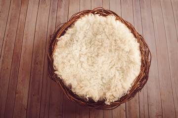 Nest with sheepskin, on a wooden floor with pink tones