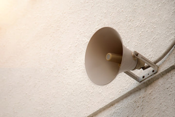 Old horn loudspeaker setting on the white wall.