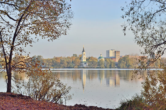 the old church and other buildings stand on the opposite bank of the lake on an autumn day