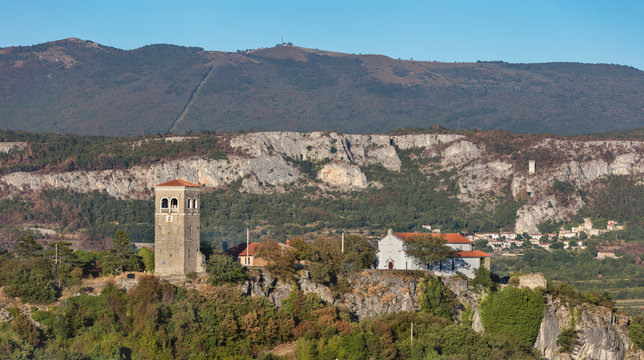 Church with remains of rural fortification in Kubed and mountain Slavnik in background, Slovenia