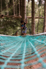 LITTLE CHILD CLIMBING IN SAFETY STRAPS IN TRACK EQUIPMENT  IN TREE TOP ADVENTURE PARK