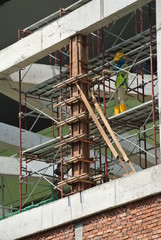 Construction workers fabricating column timber form work and reinforcement bar at the construction site in Malacca, Malaysia. 