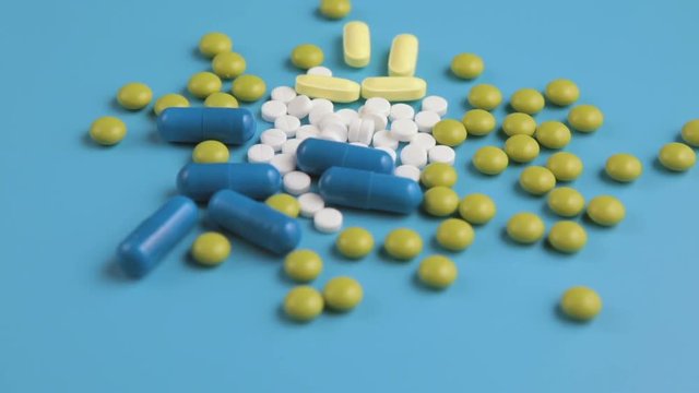 Medical multicolored pills rotation on blue background
