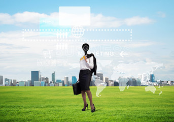 Camera headed woman standing on green grass against modern cityscape