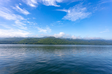 Landscape of the mountain and The ship is on the river with blue sky in the morning. View of the mountain with blue sky at Srinakarin Dam , Kanchanaburi province , Thailand.