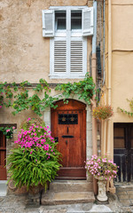 Fototapeta na wymiar Front door of a residence in the old center of Cannes decorated with flowerpots