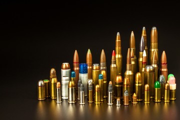 Different types of ammunition on a black background. Sale of weapons and ammunition. The right to hold a gun. - obrazy, fototapety, plakaty