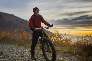 Tourist rides a bike with wide wheels along the shore of Lake Baikal.