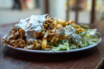 Dönerteller mit Huhn Hühnerfleisch, Knoblauch Soße, Pommes und Salat an Dönerbude Holz Tisch