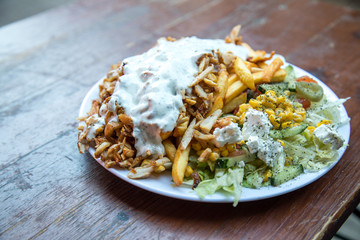 Dönerteller mit Huhn Hühnerfleisch, Knoblauch Soße, Pommes und Salat an Dönerbude Holz Tisch