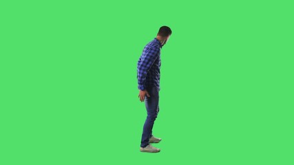 Confused young man searching for something lost on the ground and in pockets. Full body isolated on green screen background. 