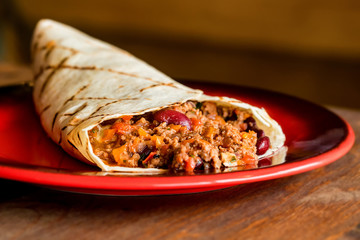 Delicious burrito with minced meat on plate close
