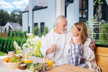 Morning atmosphere. Beaming lovely couple enjoying extremely cozy morning atmosphere together while having breakfast outside