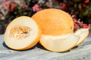 Whole and sliced melon on wooden table outdoors