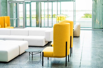 Office waiting area interior with white sofas and yellow chairs