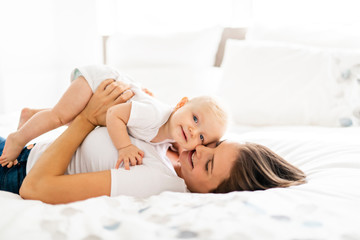 mother with baby on bed having good time