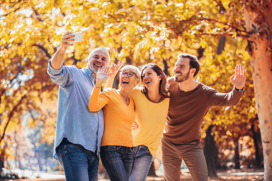 Smiling family on an autumns day in park make selfie photo.