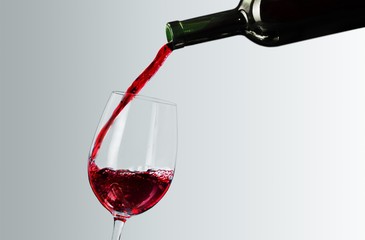 Pouring red wine in a glass isolated on white background