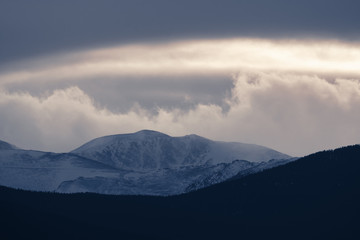 Dramatic winter storm blows over a cold barren landscape at sunset