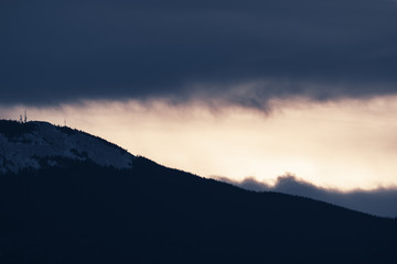 Dramatic winter storm blows over a cold barren landscape at sunset
