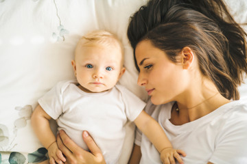 mother with baby on bed having good time