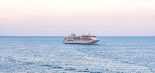Passenger ship cruising on water at sunset