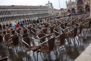 empty chairs in front of the cafe on St. mark's square in cloudy weather
