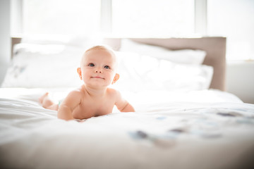 Cute baby girl lying on white sheet at home