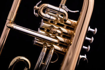 A part of a four valve lacquered flugelhorn on a black background. A brass instrument common to...