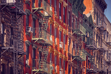 Old buildings with fire escapes at sunset, color toning applied, New York City, USA.