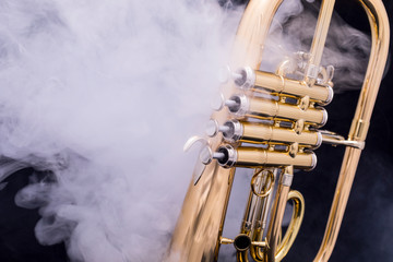 A four valve lacquered flugelhorn in smoke on a black background