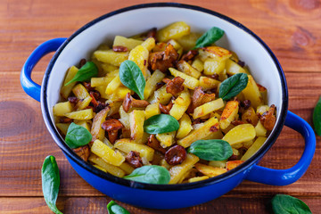 Fried potatoes with chanterelle mushrooms on a wooden table. Traditional Russian dish