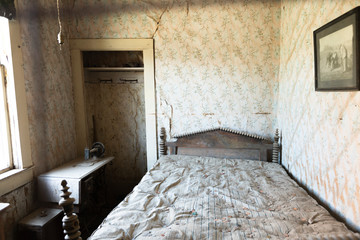 Bodie Ghost Town, an abandoned room with an old bed, a picture on the wall and a sewing machine