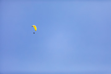 A person with a parachute up in the air on a blue sky